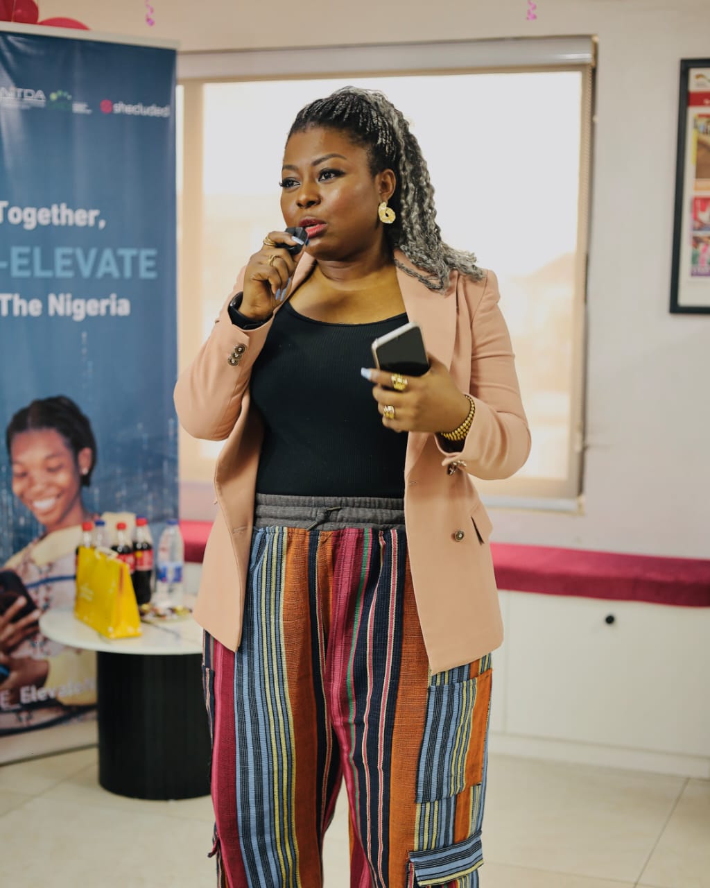 Joan Adu speaking into a microphone at a professional event.